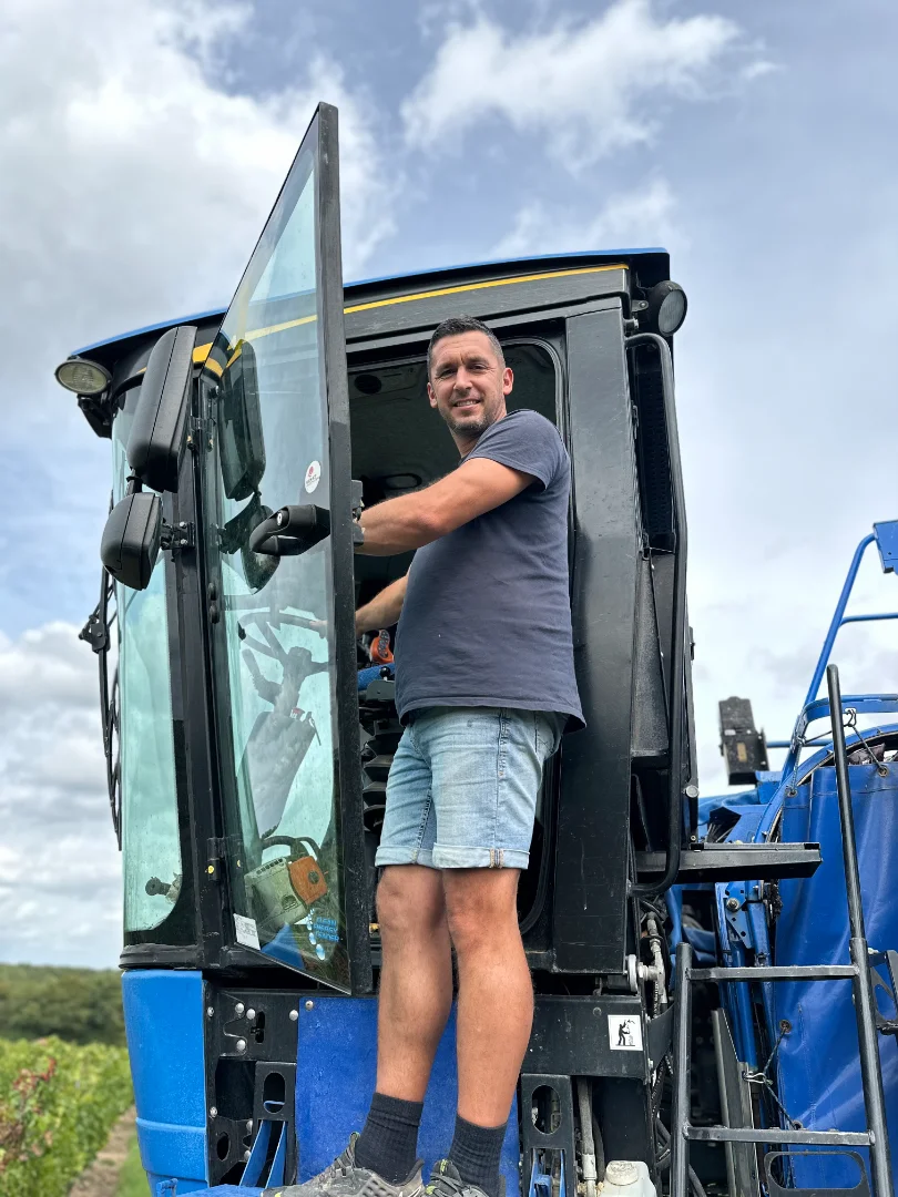 Ludovic le chef de culture, dans son engin de récolte lors d'une journée de vendange ensoleillé.