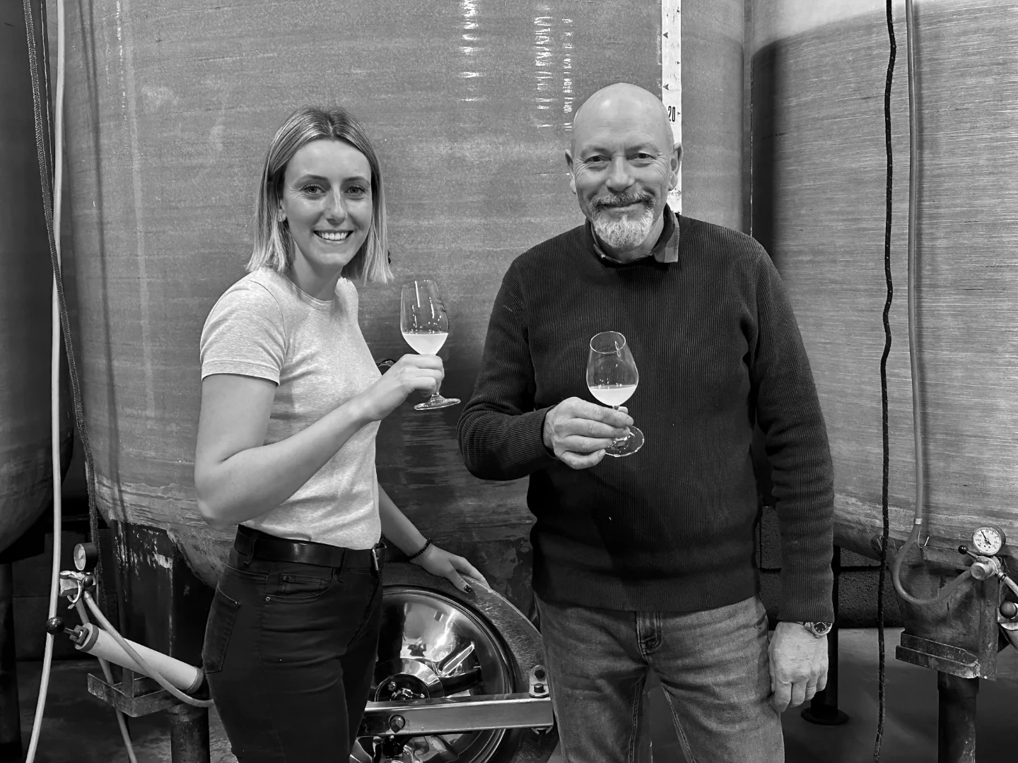 Marine et Didier dans la cave du domaine Delaunay, devant les cuves. Souriants avec un verre à la main.